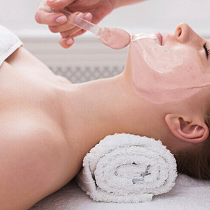 Woman gets face mask by beautician at spa